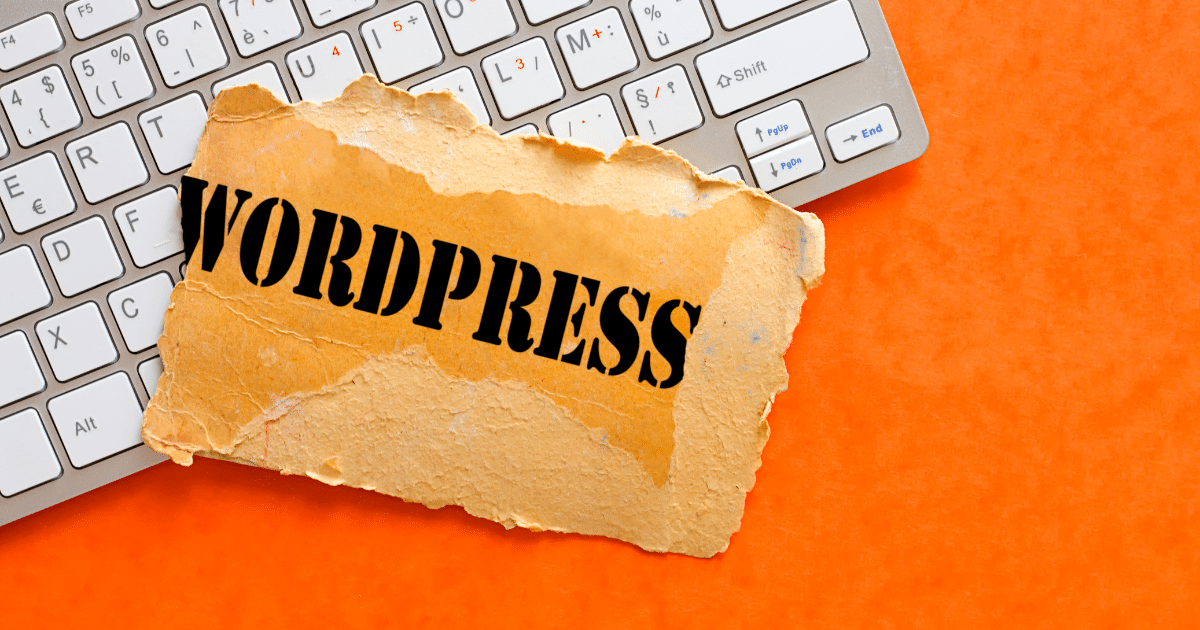 Teclado de ordenador con la palabra WordPress impresa en un papel sobre fondo naranja, representando la configuración de widgets en WordPress.