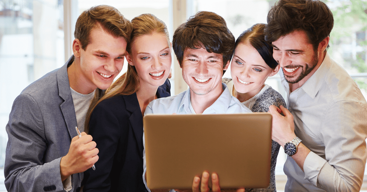 Grupo de 5 personas felices celebrando la identidad digital ONG frente a un ordenador portátil.
