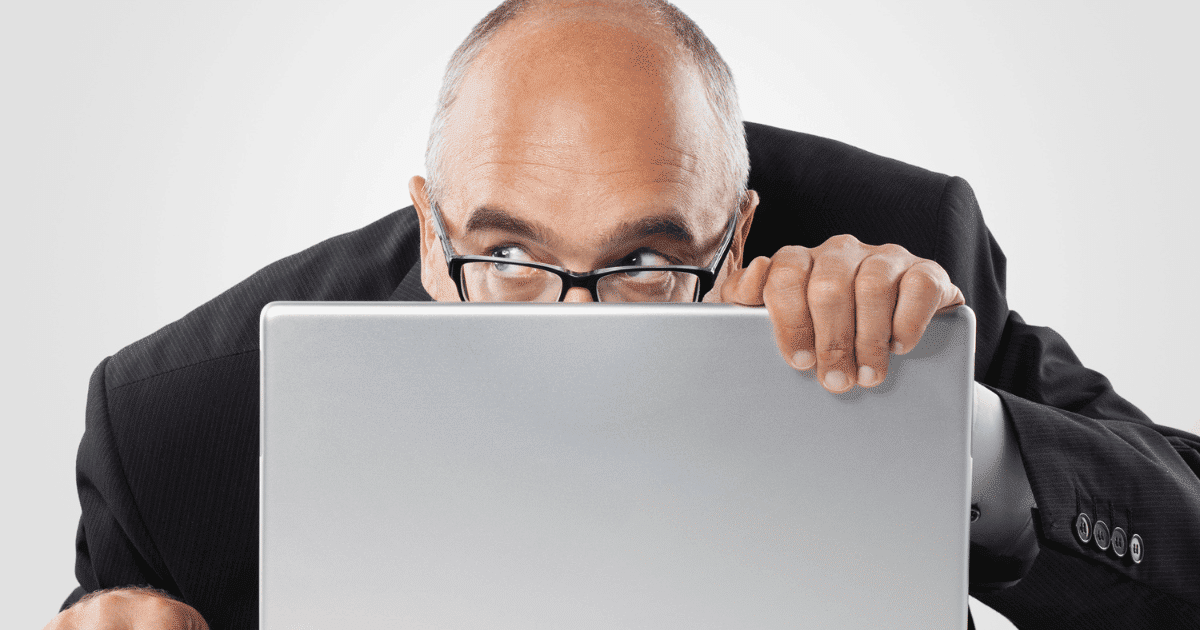 Hombre asomándose detrás de un monitor vigilando copias de seguridad web