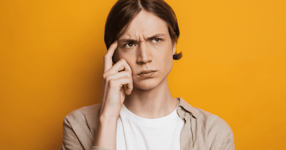 Primer plano de un joven con actitud pensativa, con la mano apoyada en la cabeza y gesto de duda frente a una pantalla de ordenador. La imagen representa el proceso de decisión de una asociación u ONG al elegir entre un blog o una web para su estrategia digital.